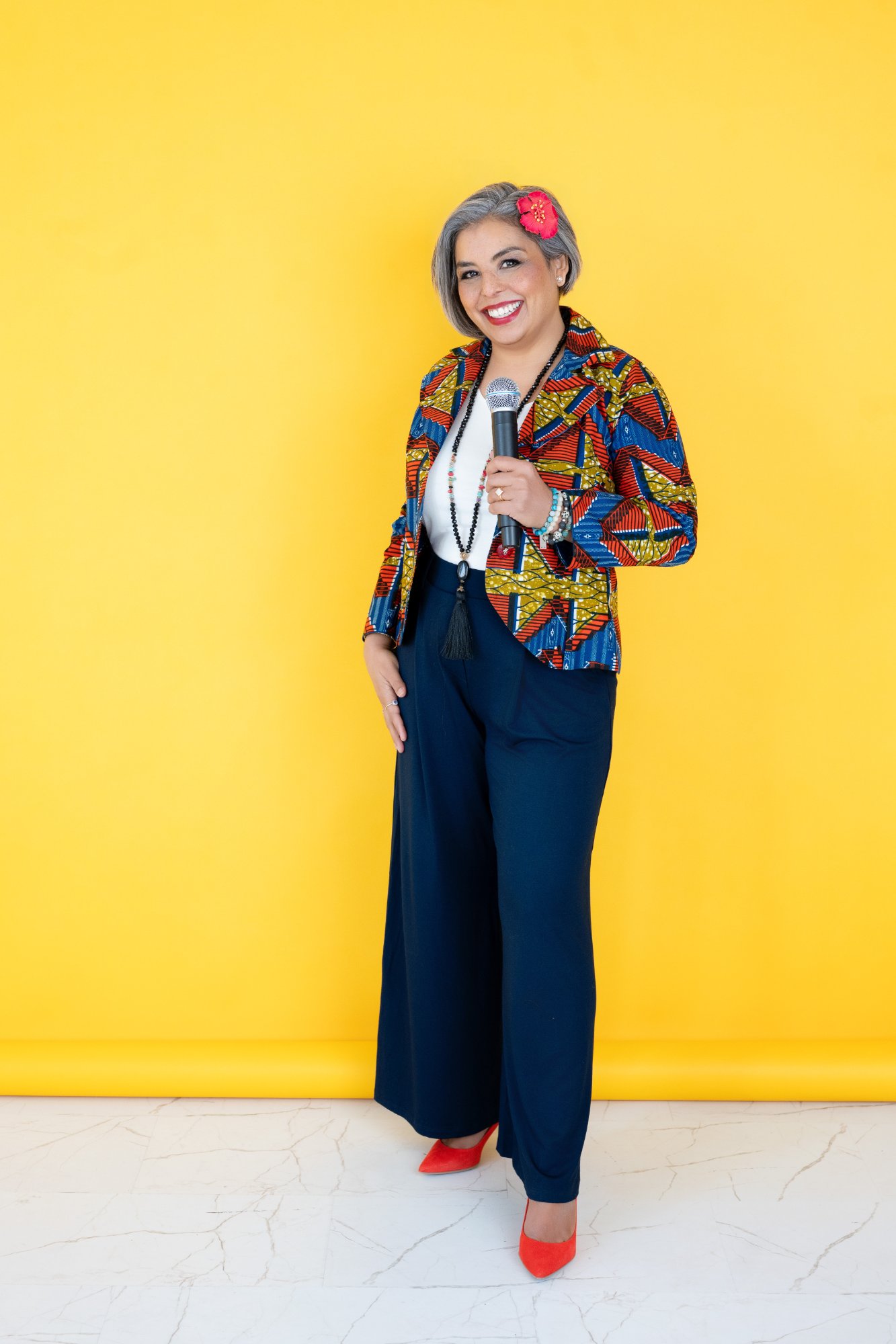 Karen Craggs standing with microphone, yellow background