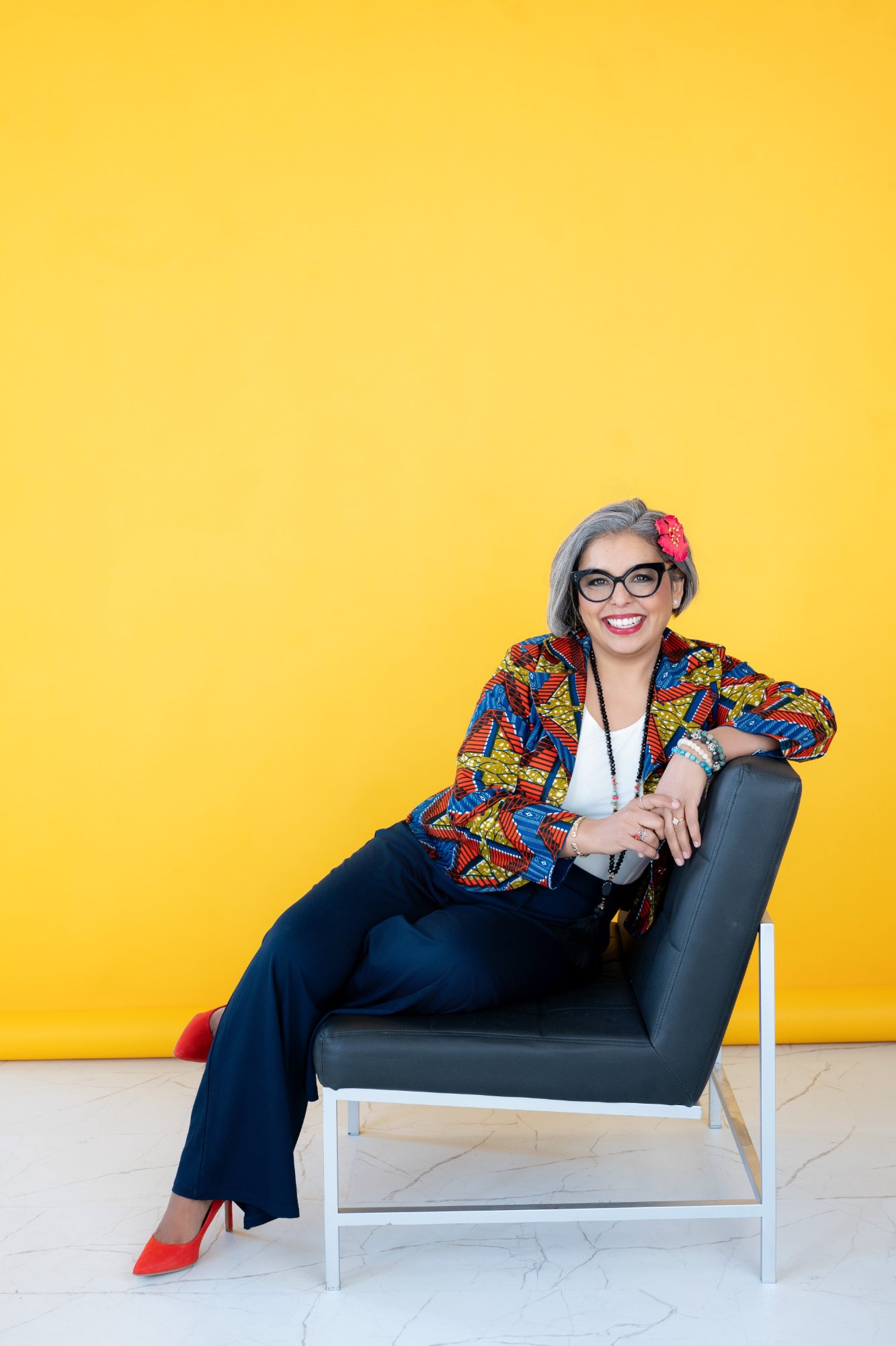 Karen Craggs seated in chair, yellow background
